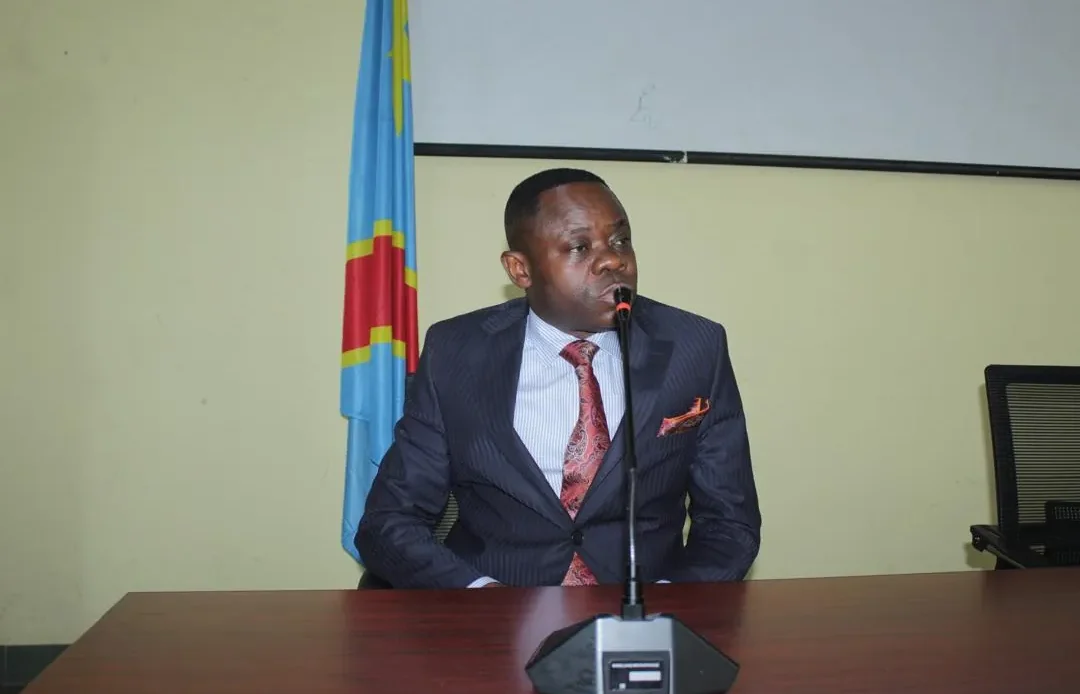 Un intervenant s'exprime à la tribune, devant le drapeau de la RDC