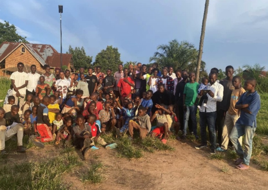 Grand groupe de jeunes et d'enfants dehors, devant des maisons